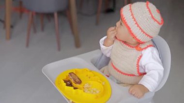 Bebek sütten kesme konsepti. O, evde kahvaltı yaparken sandalyesinde otururken elleriyle içer.