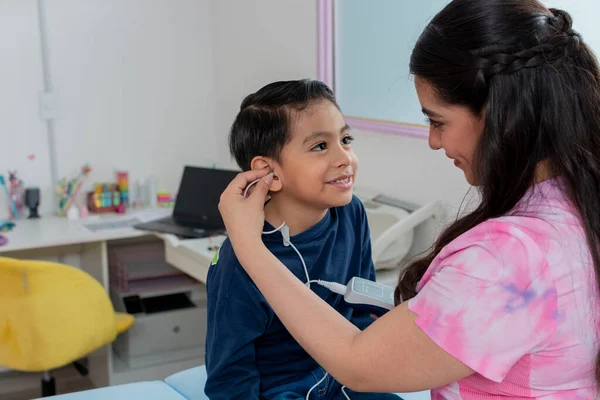 Nurse placing a headset on a child to perform a hearing test in the pediatric clinic, with copy space