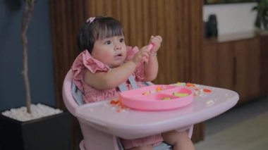 Yemek yemek istemeyen küçük kız sandalyesinde otururken kaşıkla oynuyor. bebek sütten kesilme kavramı