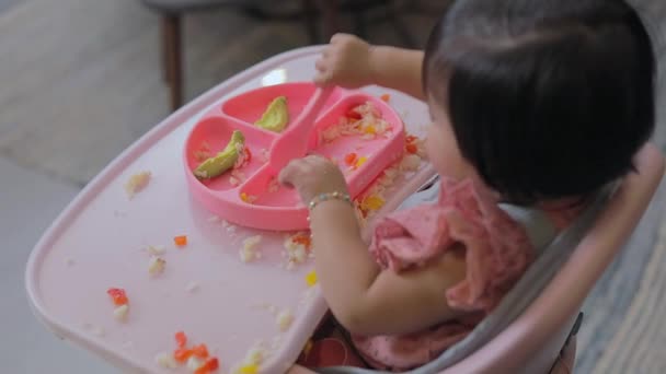 一个女孩坐在椅子上 用她的硅胶盘和勺子吃饭的镜头映入眼帘 Blw概念 — 图库视频影像