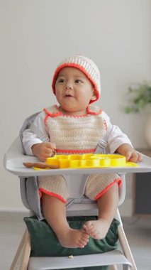 Bebek koltuğunda otururken yemek yerken gülümsüyor. bebek bakımı