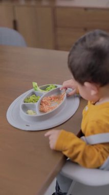 Bir çocuk ondan yemek yerken, kırmızı bir tabağın üst görüntüsü. Bebek sütten kesme konsepti