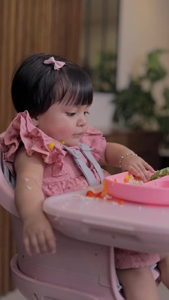 彼女の椅子に座っている少女のクローズアップは 彼女の手で食べ物を食べて手をつかむ — ストック動画