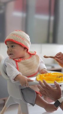 Latin bebek kaşıkla yemek verilirken yemek yemek istemiyor. Bebek sütten kesme konsepti