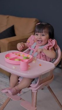 Gülümseyen kız sandalyesinde otururken kollarını açıyor. Bebek için tamamlayıcı yemek. BLW