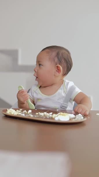 Bebé Latino Masticando Una Cuchara Mientras Come Mientras Está Sentado — Vídeo de stock