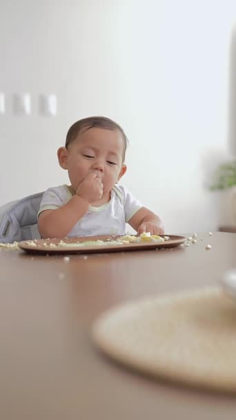 婴儿用手吃鸡蛋 坐在家里的桌子旁 — 图库视频影像