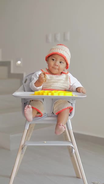 Bayi Duduk Kursinya Makan Dengan Tangannya Tersenyum Sambil Melihat Kamera — Stok Video