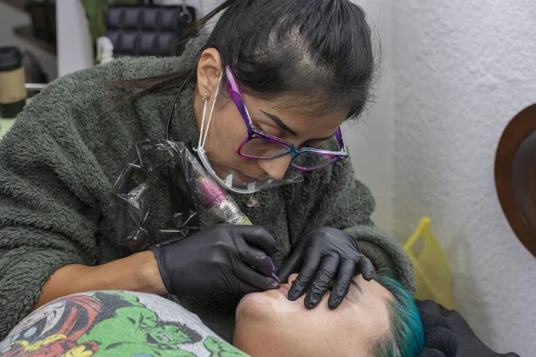 Permanent makeup on lips. Dermatological tattoo artist tattooing a womans lips to give them color