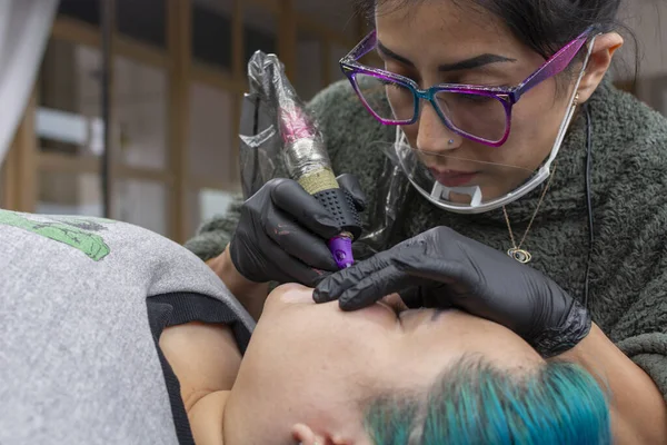 Woman tattooing a womans lips, applying permanent makeup