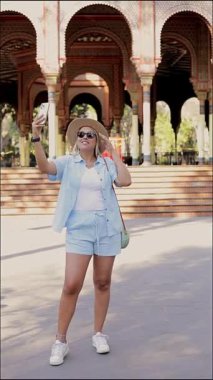 Meksika 'daki Fas büfesinde cep telefonuyla selfie çeken şapkalı bir turist kadın.