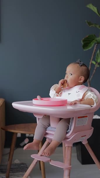 一个婴儿坐在她的椅子上 用她的手从盘子里吃东西 — 图库视频影像