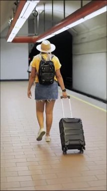 Genç gezgin kadın bavuluyla ve sırt çantasıyla Mexico City 'de bir metro istasyonunda yürüyor.