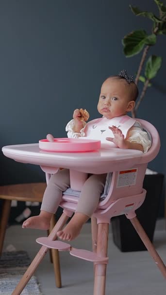 一个坐在椅子上的女婴用手吃着煎饼 — 图库视频影像
