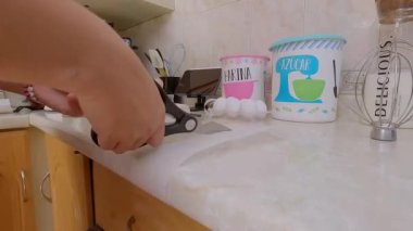 Bir kadının ellerini makasla kapayın. Pasta tepsisine koymak için balmumu kağıdı kesin.