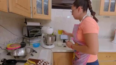 Bir kadın mutfak tezgahında pasta hazırlarken zeytinyağı ekliyor..