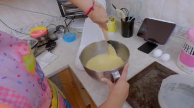 Pastayı karıştırmak için elektrikli mikseri kürekle temizleyen kadın.