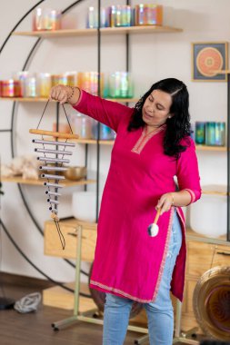 Bir müzik stüdyosunda rüzgar çanları çalan Meksikalı bir kadın Tibet şarkı kaseleri ile bir müzik seansında