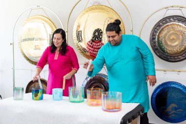 Bir müzik stüdyosunda gonglarla kristal Tibet şarkı kasesi çalan iki şifacı.