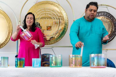 Bir müzik stüdyosunda müzik seansı sırasında kristal kaseler ve diğer enstrümanlar çalan iki müzisyen.