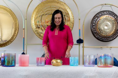 Bir müzik stüdyosunda çıngıraklı bir Meksikalı kadın ses iyileştirme seansı sırasında Tibet şarkı kaseleri çalıyor.