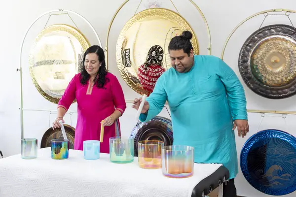 Bir müzik stüdyosunda gonglarla kristal Tibet şarkı kasesi çalan iki şifacı.