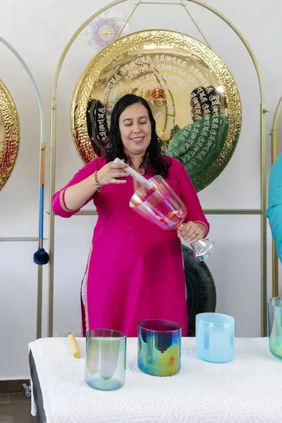 Meksikalı ses iyileştirici müzik stüdyosunda kristal kaseler çalıyor, arka planda gonglar var.