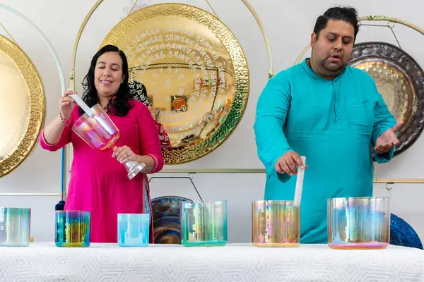 Bir müzik stüdyosunda müzik seansı sırasında kristal kaseler ve diğer enstrümanlar çalan iki müzisyen.