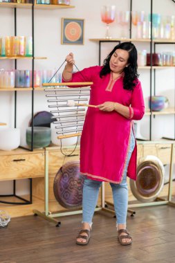 Tibet müzik kaseleri, gonglar ve diğer enstrümanlarla çevrili bir müzik stüdyosunda çalan Latin kadın.