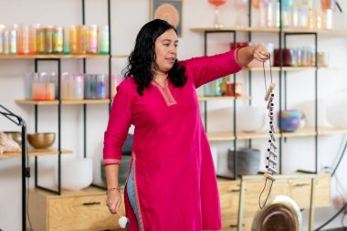 Latin Amerikalı müzik terapisti stüdyosundaki bir ses iyileştirme seansı sırasında rüzgar çanları çalıyor.