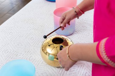 Müzik stüdyosundaki ses iyileştirme seansında tokmakla gitar çalan müzisyen, Tibet şarkı kaseleriyle çevrili.