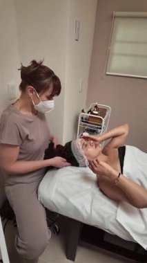 Uzman yüz bakımı yapan yetenekli bir güzellik uzmanı, profesyonel cilt bakımı ürünleri uygularken modern spa ortamında rahatlatıcı masajlar yapıyor.
