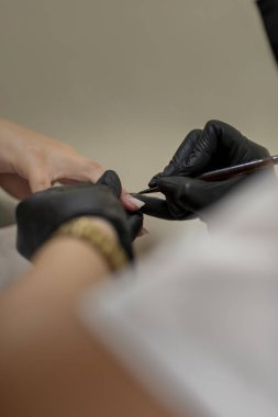 Güzellik uzmanının kaplıcada ya da güzellik salonunda manikür yaparken kadın tırnaklarına oje sürdüğü yakın plan.