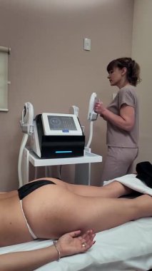 Profesyonel güzellik uzmanı kozmetik tedavi sırasında kadın hastaların kalçalarında kriyolipoliz yağ azaltma prosedürü uyguluyor.