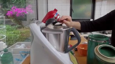 Ev yemeği dikkatli bir şekilde ölçüp yiyecek işlemcisine taze malzemeler eklerken parlak mutfak ortamında ev yapımı kiş hazırlıyor.