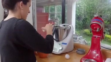 Profesyonel ev aşçısı, modern mutfak ortamında klasik ev yapımı kiş malzemelerini hazırlarken beyaz gıda işlemcisinin içine taze doğranmış soğan ekliyor.