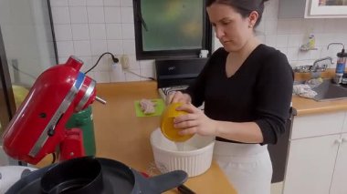 Kadın aşçı kiş malzemelerini hassasiyetle karıştırıyor, bileşenleri ustalıkla harmanlarken parlak mutfak alanında ev yapımı lezzetli hamur işlerini hazırlıyor.