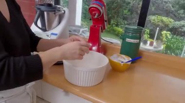 Ev yemeği kiş karışımı, yumurta çırpma ve güneş ışığında mutfak tezgahının yanında dururken seramik kaseye doldurma