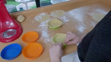 Profesyonel pasta şefi hassas mini sandviçler hazırlıyor, profesyonel mutfak çalışma alanı içinde renkli silikon kalıplara ustalıkla hamur işliyor.