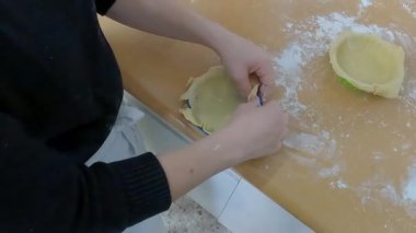 Deneyimli hamur işi şefi hassas hamuru dikkatlice katlıyor ve şekillendiriyor, profesyonel mutfak becerileri ve geleneksel ev yapımı yemek hazırlama teknikleri sergiliyor.