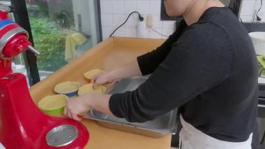 Profesyonel fırıncı mutfaktaki metal kek kutularının içinde rengarenk kiş hamuru hazırlıyor.