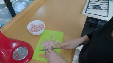 Profesyonel ev aşçısı dikkatli bir şekilde yeşil kesme tahtasında jambon doğruyor, titizlikle klasik kiş tarifi için taze malzemeler hazırlıyor.