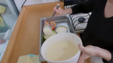 Ev aşçısı kremalı kiş hamurunu canlı turtalara döker, rahat mutfak çalışma alanı içinde gurme hamur işi yaratır.