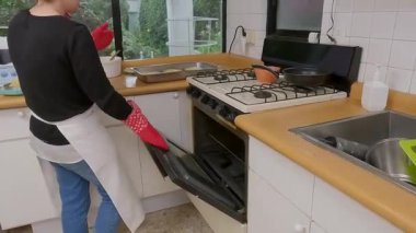 Profesyonel ev yapımı aşçı, klasik kiş lorraini yerli bir mutfak fırınına dikkatlice yerleştiriyor ve geleneksel ev yapımı yemekleri pişirme uzmanlığıyla hazırlıyor.