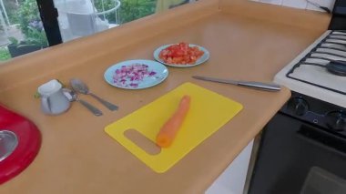 Ahşap mutfak tezgahında doğranmış taze sebzeler, yemek pişirme malzemeleri, kesme aletleriyle mutfak çalışma alanı.