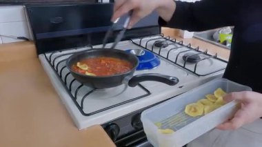 Profesyonel kadın aşçı dikkatlice, profesyonel mutfak mutfağında pişen domates sosuna taze mantı ekliyor.