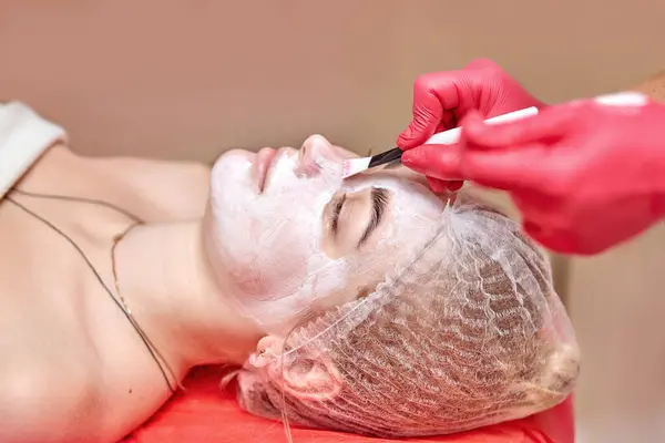 Yüzünde krem maske olan bir kız.
