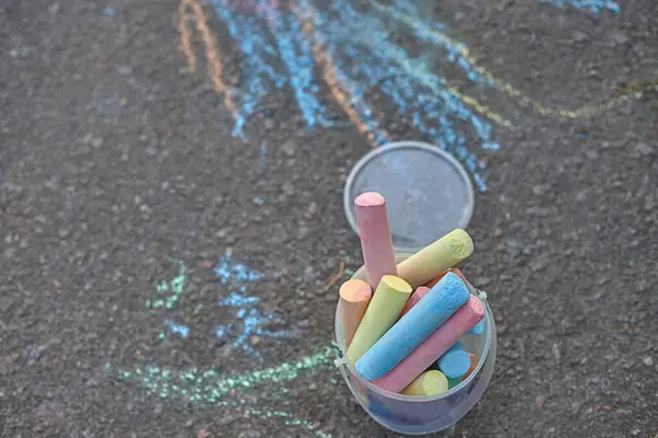 Plastik bir kutuda asfaltta bir kova çok renkli tebeşir..