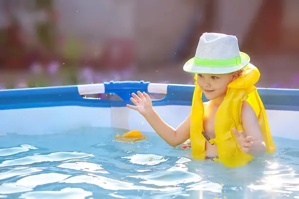 Yüzme havuzunda banyo yapan can yeleği giymiş bir çocuk. Ev havuzu