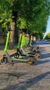 Şehrin arka planında elektrikli scooterlar. Sağlıklı yaşam tarzı, çevresel koruma, eko kavramı